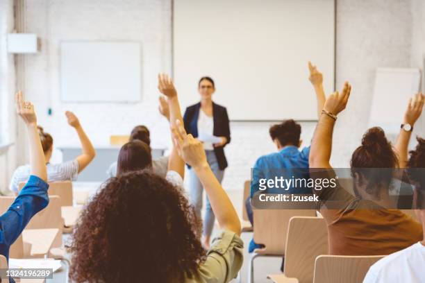 university students answering to female teacher - classroom stockfoto's en -beelden