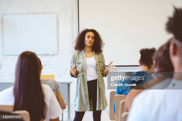 young woman giving speech in classroom - palestra imagens e fotografias de stock