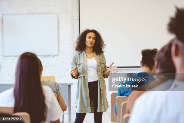 young woman giving speech in classroom - speech imagens e fotografias de stock