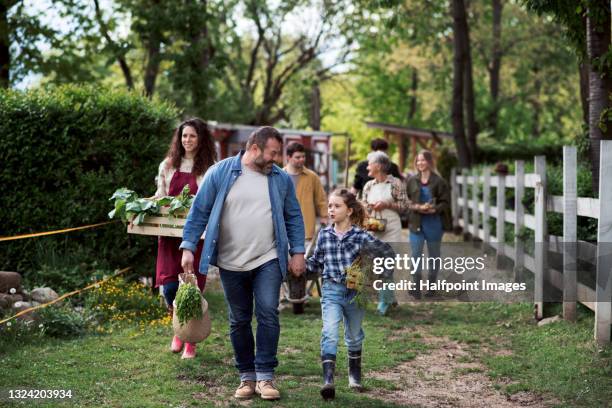 group of people with vegetables walking on farm, community farming. - farmhand stock-fotos und bilder