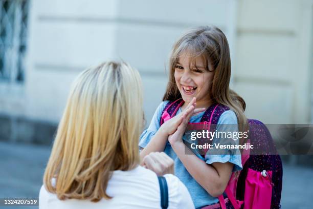 la maestra o la madre envían o da la bienvenida a la niña a la escuela - organismo-vivo fotografías e imágenes de stock