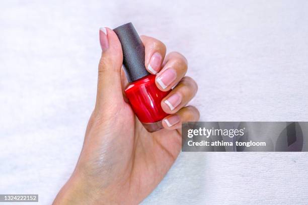 hand holds bottle of red nail polish. - rubin stock-fotos und bilder