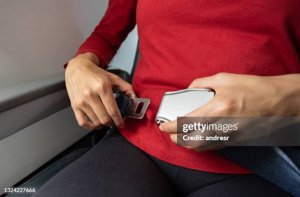 close-up on a passenger traveling by plane and fastening her seatbelt - seat belt stock pictures, royalty-free photos & images