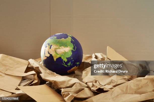 a world globe on a stack of paper recyclables - wrapping stock pictures, royalty-free photos & images