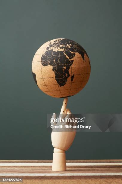 a world globe balanced on the finger of a wooden hand - desktop globe stock-fotos und bilder