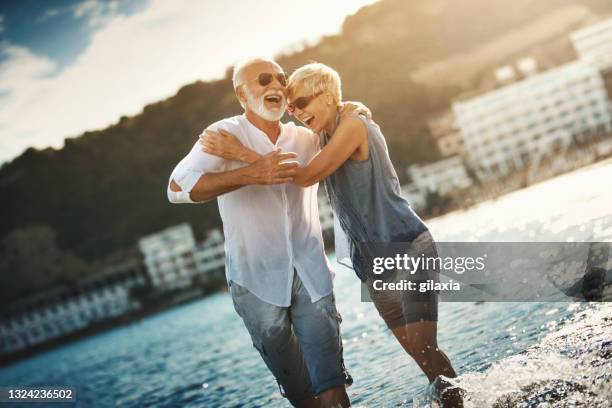 senior couple walking on the beach at sunset. - couple on beach sunglasses stock pictures, royalty-free photos & images