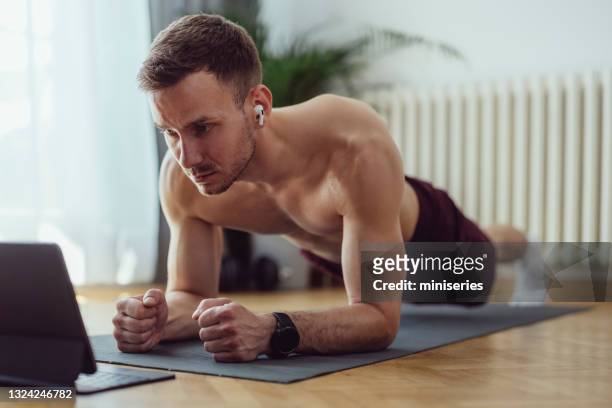 home workout: fit young man doing exercise at home - man muscular build stock pictures, royalty-free photos & images