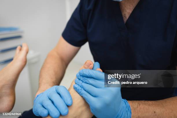 podiatrist checks a patient's foot inside his clinic - medical footwear stock pictures, royalty-free photos & images