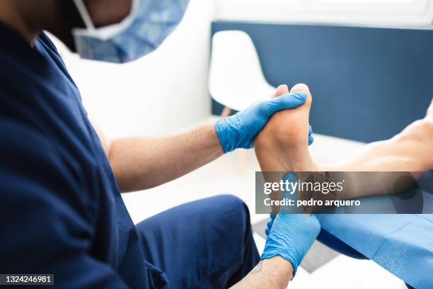podiatrist checks a patient's foot inside his clinic - podiatrist stock-fotos und bilder