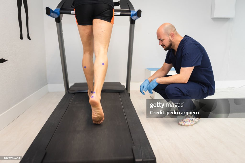 Podiatrist checking the footprint of a patient walking on an electrical treadmill