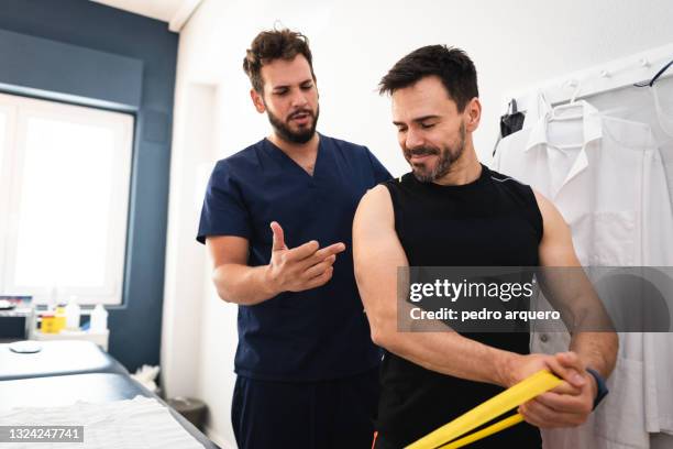 chiropractor treating patient shoulder inside his clinic - man touching shoulder stockfoto's en -beelden