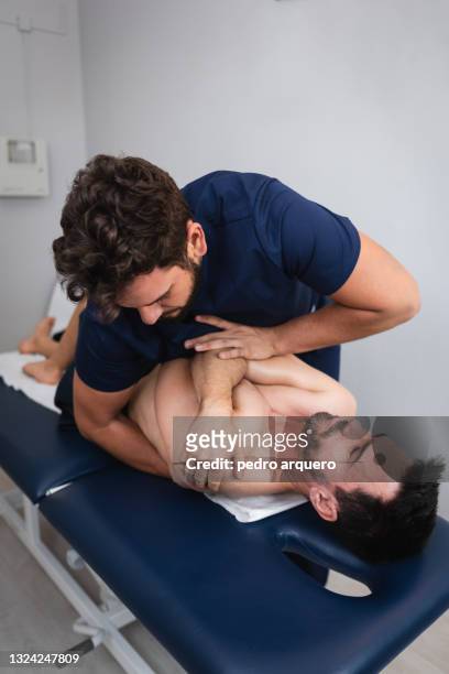 chiropractor performing an adjustment on an athlete's back - kinésithérapeute photos et images de collection