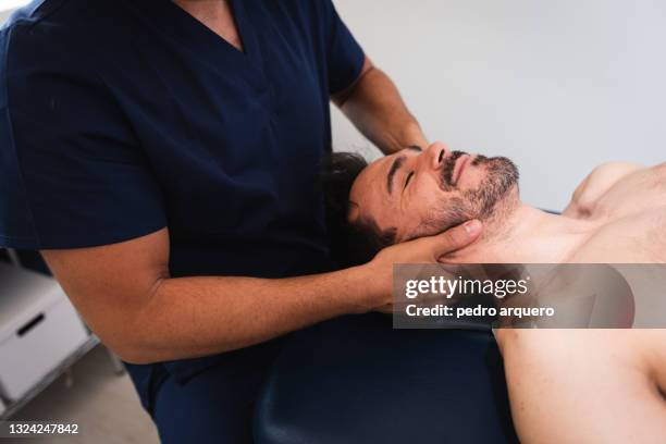 chiropractor performing an adjustment on a patient's neck - osteopathie stockfoto's en -beelden