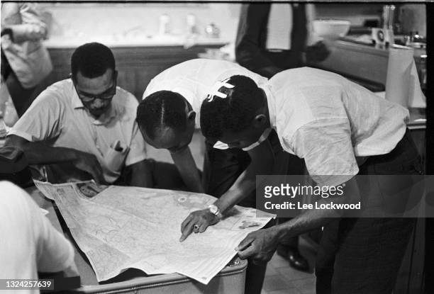 Along with unidentified others, American Civil Rights activist John Lewis , his head bandaged, studies a map on a table in a temporary safe house...