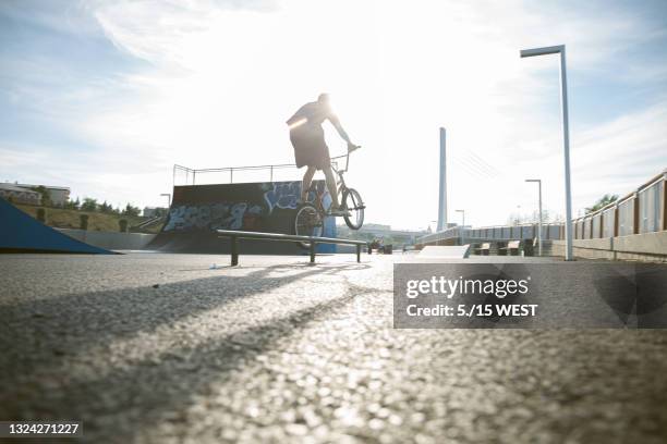 teenager auf dem fahrrad führt tricks auf einem skatepark - bmx stock-fotos und bilder