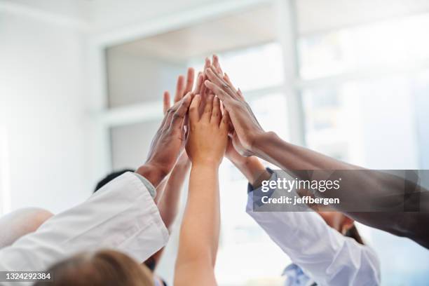 shot of a set of hands high fiving in victory - a team 個照片及圖片檔