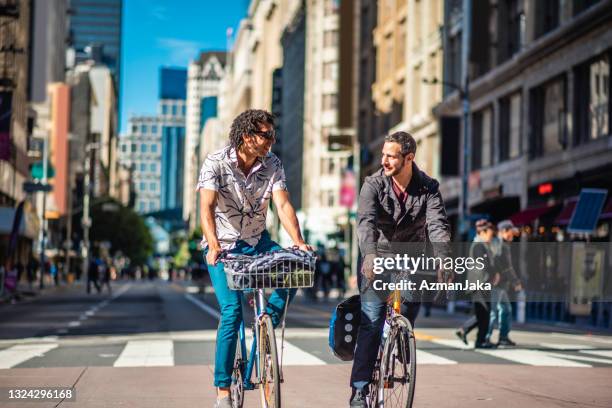 male bikers in late 30s riding in downtown car-free zone - city life authentic stockfoto's en -beelden