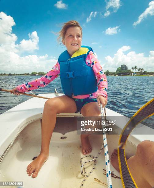 young girl confidently sails a boat on a lake in summer - sunfish sailboat stock pictures, royalty-free photos & images