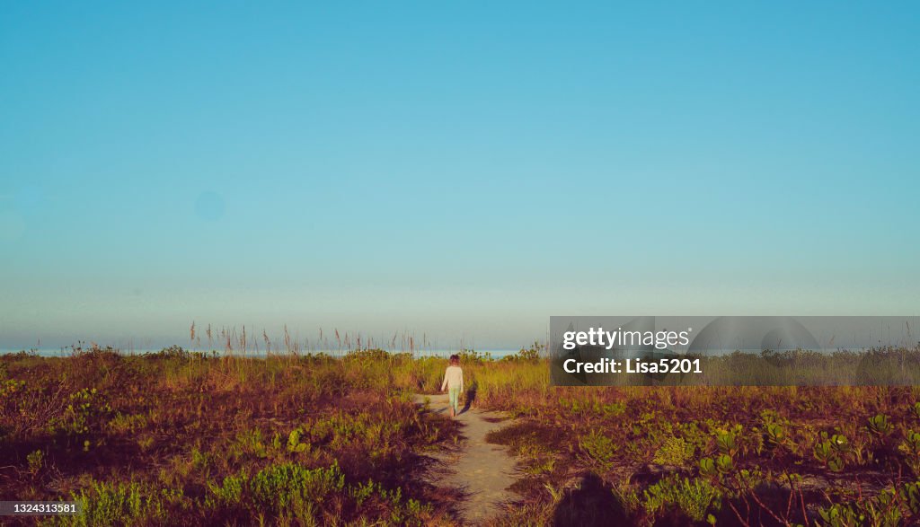 Tranquil scene, child walks idyllic path to a beautiful deserted beach
