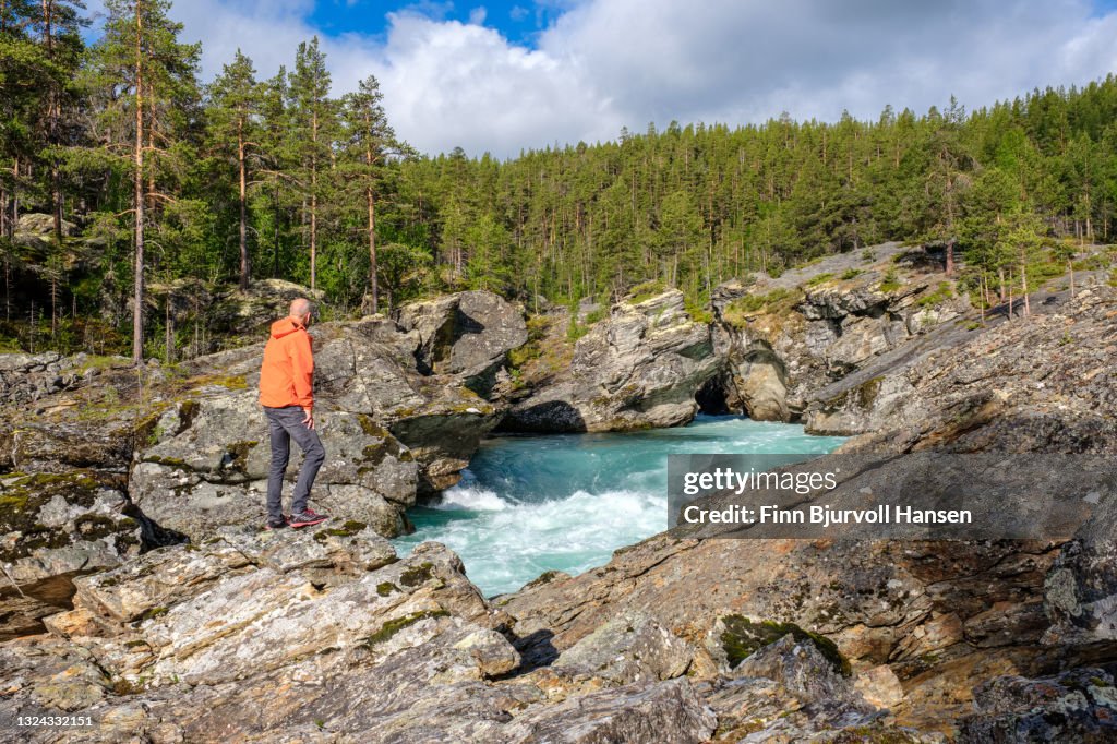 Senior male standing on a rock watching the river at ridderspranget Norway