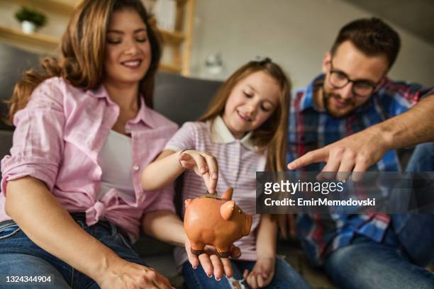 portrait of a family saving money in piggybank - couple saving piggy bank stock pictures, royalty-free photos & images