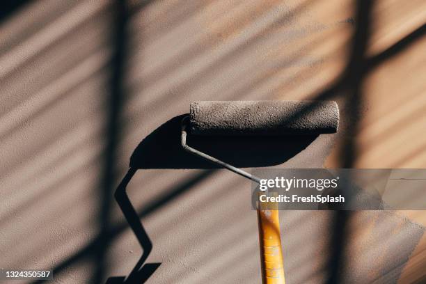 close up foto von paint roller auf einer wand - wand streichen stock-fotos und bilder