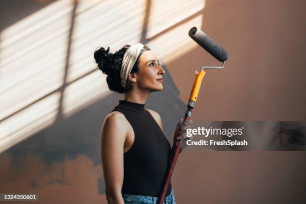 femme souriante posant avec un rouleau de peinture - peintre photos et images de collection