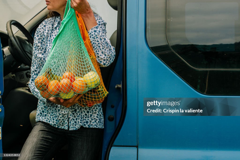 Close up of a woman with colorful reusable net bags in a blue van