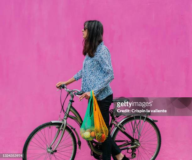 woman with classic dutch bike with reusable bags with a sustainable purchase on pink background - blank tote bag stock pictures, royalty-free photos & images