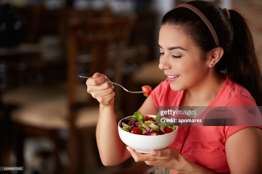 Close-up of a Hispanic cute young woman eating vegan salad at lunch