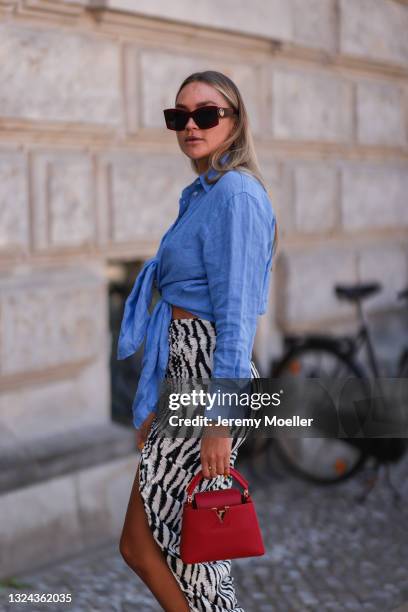 Nina Suess wearing red Lanvin shades, blue Zara shirt, black and white Jacquemus skirt and red Louis Vuitton leather bag on June 16, 2021 in Berlin,...