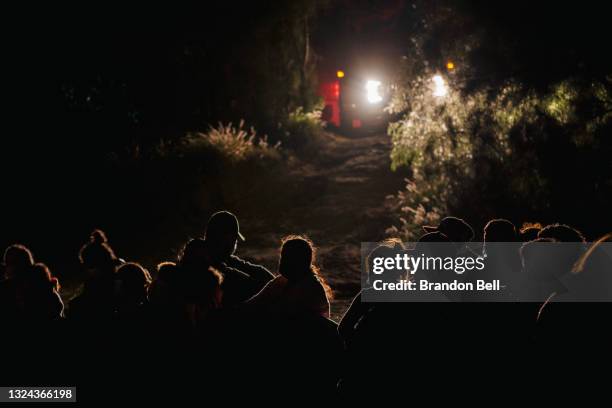 Immigrants seeking asylum wait to be accounted for and taken to a border patrol processing facility after crossing the Rio Grande into the U.S. On...