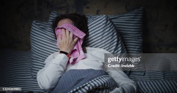 la mujer madura está tratando de dormir en la cama, pero sufre de calor - sudor fotografías e imágenes de stock