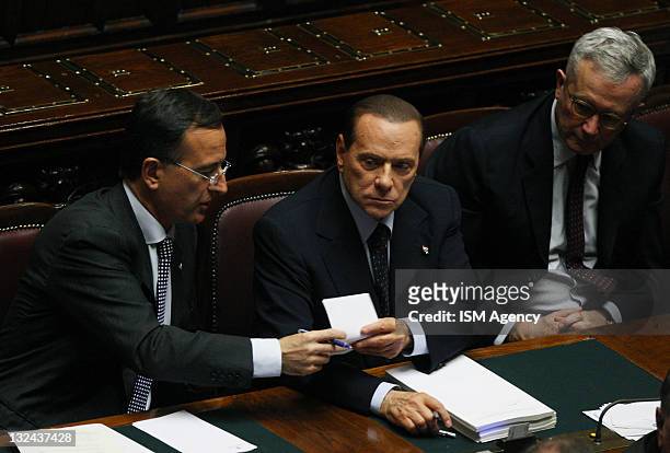 Italian Minister of Foreign Franco Frattini and Italian Prime Minister Silvio Berlusconi pass a piece of paper as Italian Finance Minister Giulio...