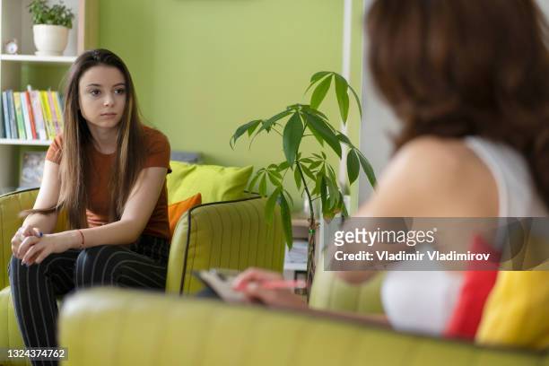 a sad teen is discussing her problems with a therapist - consoling teenager stock pictures, royalty-free photos & images