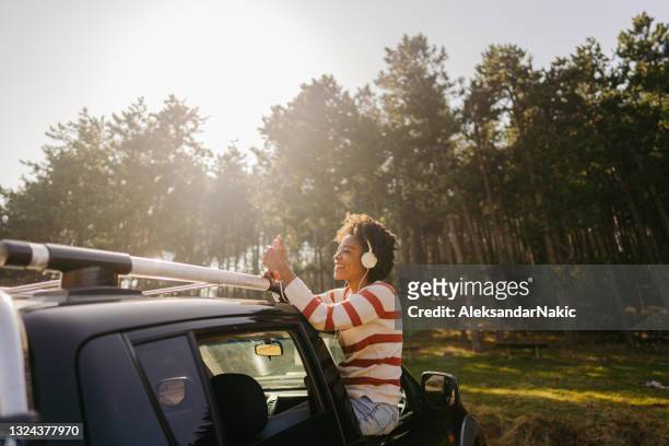 junge frau mit smartphone während einer roadtrip - elektro auto stock-fotos und bilder