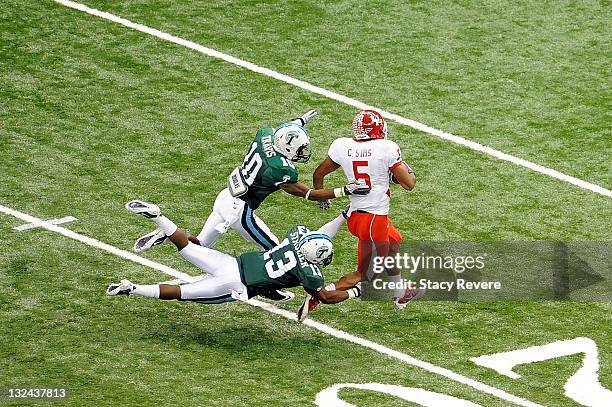 Charles Sims of the University of Houston Cougars is tackled by Derrick Strozier and Ryan Travis of the Tulane Green Wave during a game being held at...