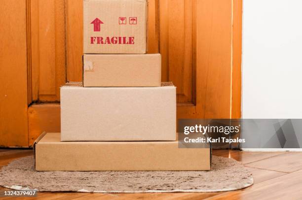 stacks of carton boxes on a front door - send parcel stock pictures, royalty-free photos & images