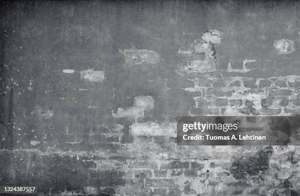 front view of an old, dirty, damaged and plastered wall. plaster is partly peeled off revealing old bricks. - bakstenen muur stockfoto's en -beelden