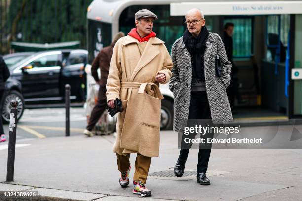 Guest wears a gray beret cap, a hooded red sweatshirt, a silver rings, a beige oversized wool trench coat, camel suit pants, black leather gloves,...