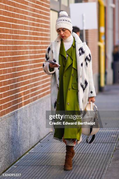 Guest wears a white wool pattern beanie, a white brown striped turtleneck pullover, a long multicolor pattern skirt, a long green shiny silk blazer...