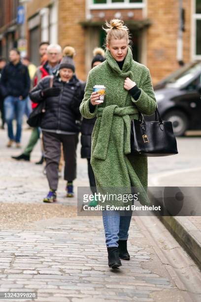 Guest wears black turtleneck wool pullover, a green belted long fluffy coat, a gold and diamond ring, a black shiny Ralph Lauren handbag, blue faded...
