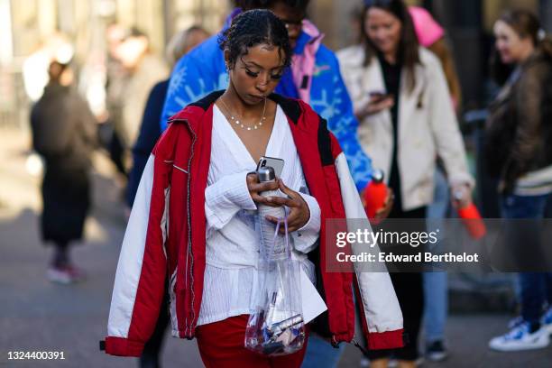 Guest wears pearls earring, silver and diamond earrings, a diamond pendants necklace, a white ribbed V-neck belted shirt, a white red and black rain...