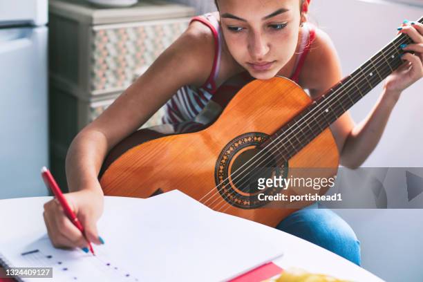 teenage mädchen lernen online, wie man gitarre spielt - writing instrument stock-fotos und bilder