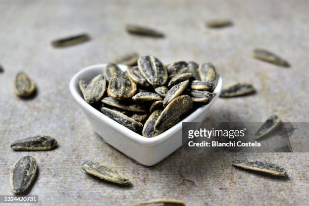heart-shaped bowl with salted sunflower seeds - sonnenblumenkerne stock-fotos und bilder
