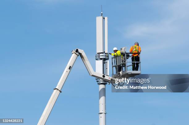 Workers install a 5G mobile phone mast using a cherry picker on June 8, 2021 in Bristol, England.