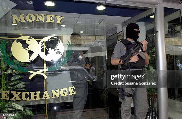 Masked Mexican police officer stands guard during a raid of a currency exchange store June 21, 2001 in Mexico City. The raid was part of "Operation...