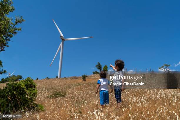 rüzgar enerjisini elektrik enerjisine dönüştüren rüzgar gülü ile tanışan küçük çocuklar - elektrik stockfoto's en -beelden