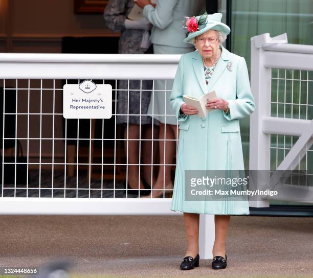 Queen Elizabeth II holds a racecard as she stands in the parade ring on day 5 of Royal Ascot at Ascot Racecourse on June 19, 2021 in Ascot, England.