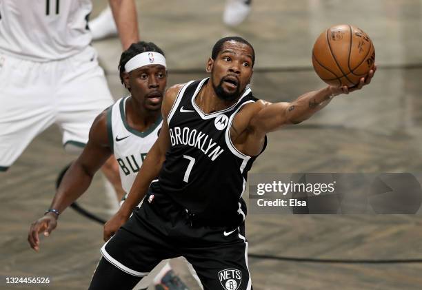 Kevin Durant of the Brooklyn Nets grabs the loose ball as Jrue Holiday of the Milwaukee Bucks defends in the first half during game seven of the...